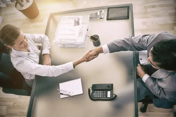 An overhead view of people shaking hands over a desk
