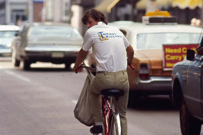 An old photo of a Thomas Blueprint delivery person on a bicycle